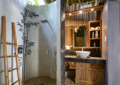 Cottage bathroom with painting of bamboo plant in the shower and basin unit built of bamboo and stone.