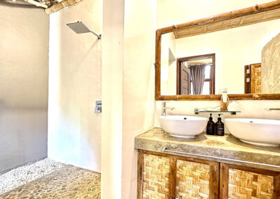 Villa bathroom with twin washbasins and semi outdoor shower, designed in wood and bamboo.