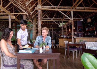 Friendly waiter serving traditional Filipino dish to a romantic couple at Buko Restaurant.