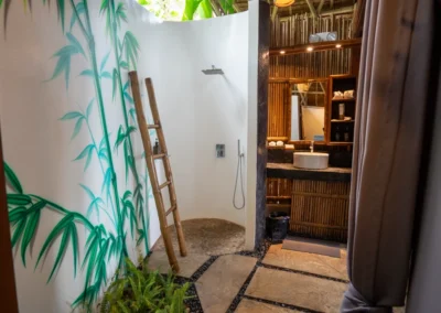 Cottage bathroom with painting of bamboo plant in shower and basin unit built of bamboo and stone.