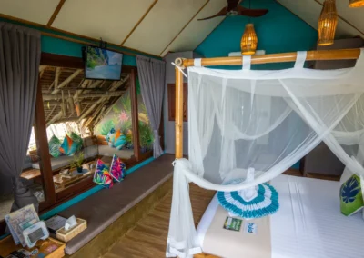 Standard cottage bedroom with bamboo framed king-size bed with mosquito netting, ceiling fan and TV